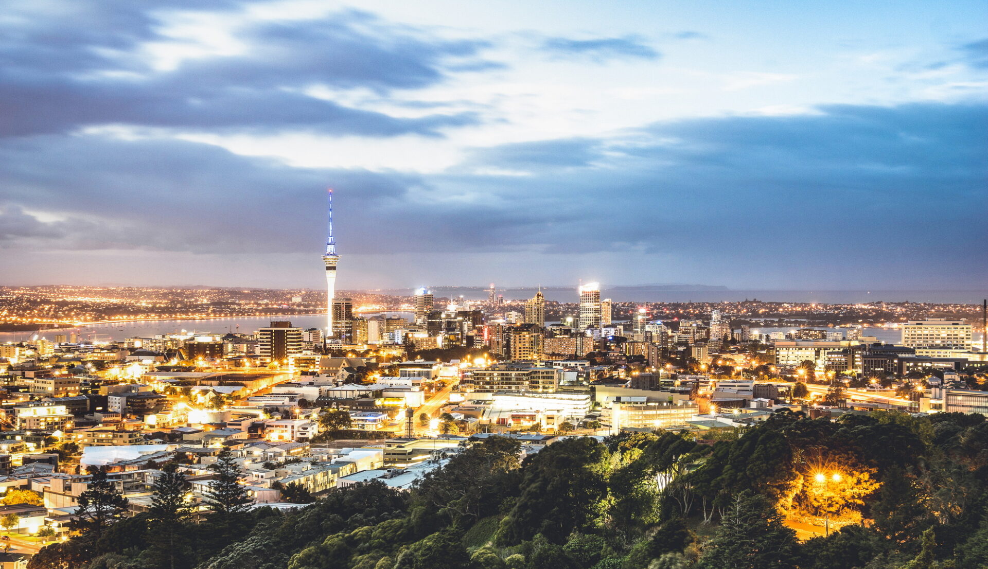 Vue aérienne de la ligne d'horizon d'Auckland à partir du mont Eden après le coucher du soleil pendant Blue Hour - ville moderne de Nouvelle-Zélande avec un panorama de paysage nocturne majestueux - Filtre amélioré sur les lumières nocturnes